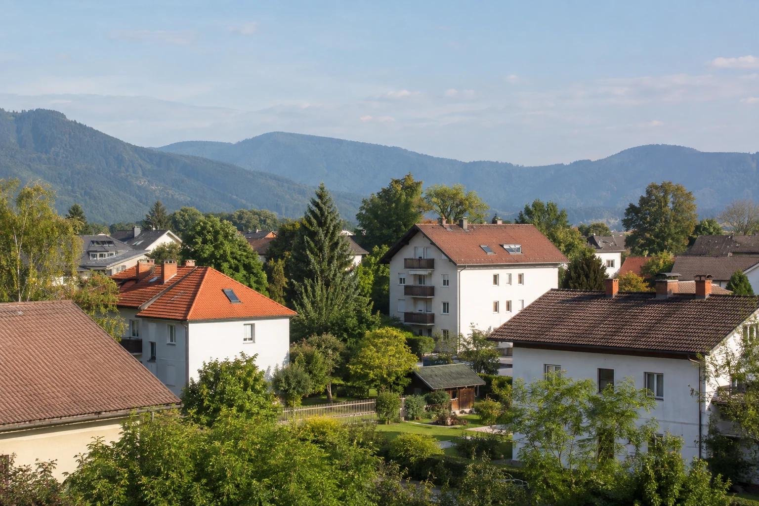 Österreichischer Wohnort mit hellen Häusern, Gärten und grünen Alpenausläufern